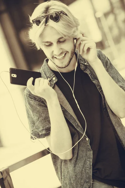 Hipster man standing with earphones talking on phone — Stock Photo, Image