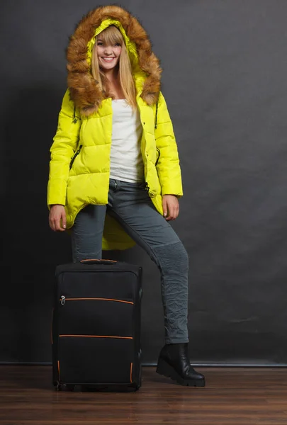 Gelukkig jonge vrouw in warme jas met koffer. — Stockfoto