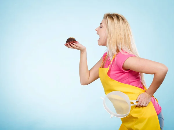 Женщина держит шоколадный кекс на пороге укуса — стоковое фото