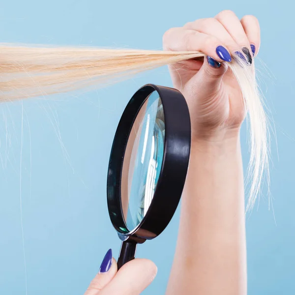 Femme regardant les cheveux à travers la loupe — Photo