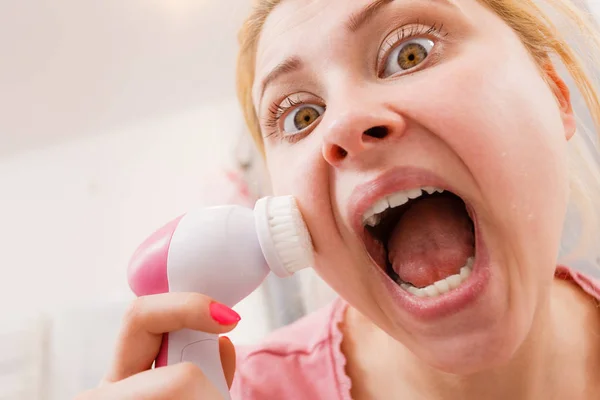 Mulher chocada usando escova de limpeza facial — Fotografia de Stock