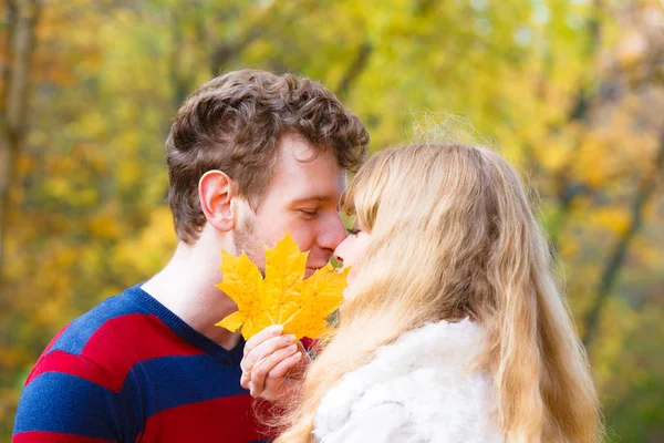 Casal com folha de bordo beijando no parque de outono — Fotografia de Stock