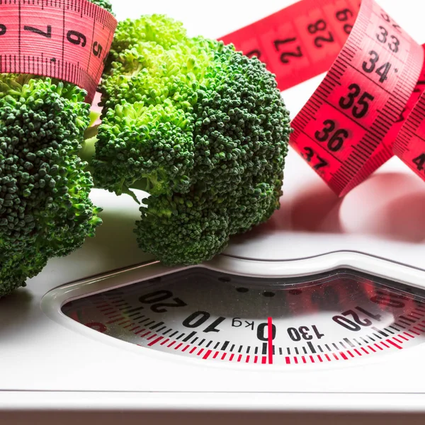 Broccoli with measuring tape on weight scale. Dieting