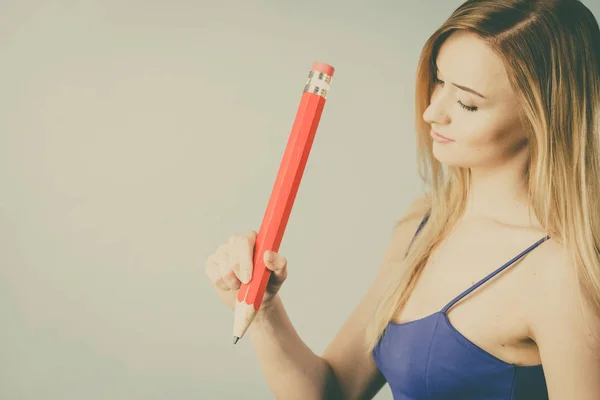 Positive woman holds big pencil in hand — Stock Photo, Image