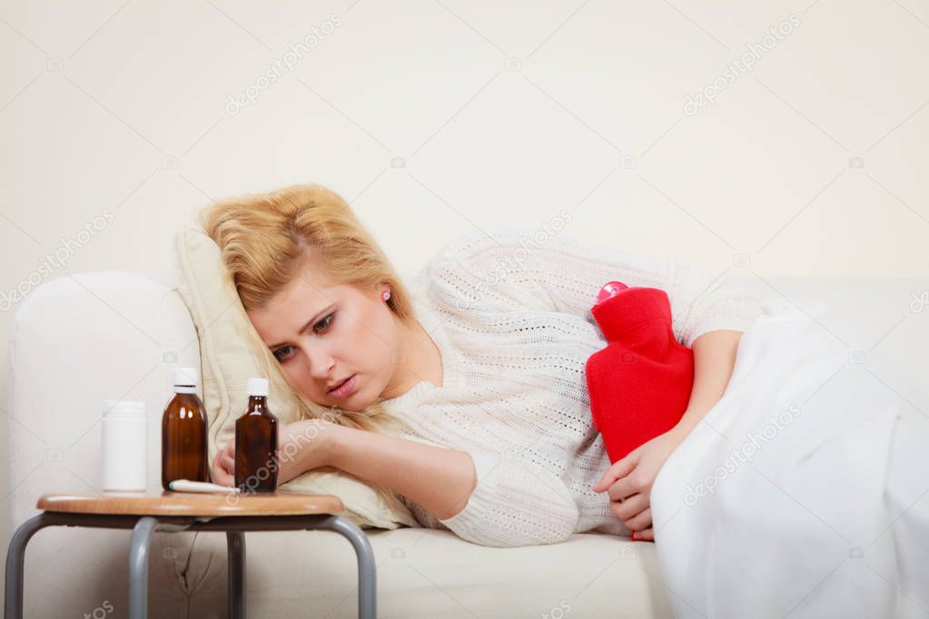 Woman feeling stomach cramps lying on cofa