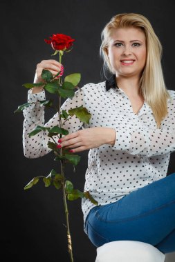 Koltukta oturan kız kırmızı gül, karanlık üzerinde tutar..