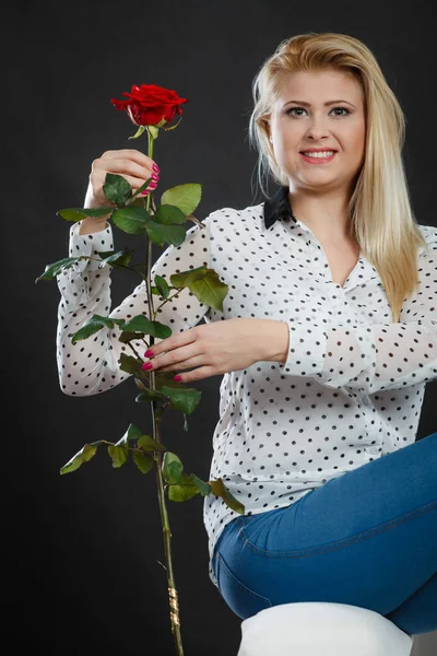 Koltukta oturan kız kırmızı gül, karanlık üzerinde tutar..