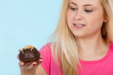 Çikolatalı kek tutan kadın ısırmak üzere.