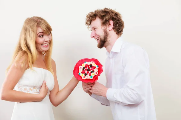 お菓子たくさん花を持つ幸せなカップル。愛. — ストック写真