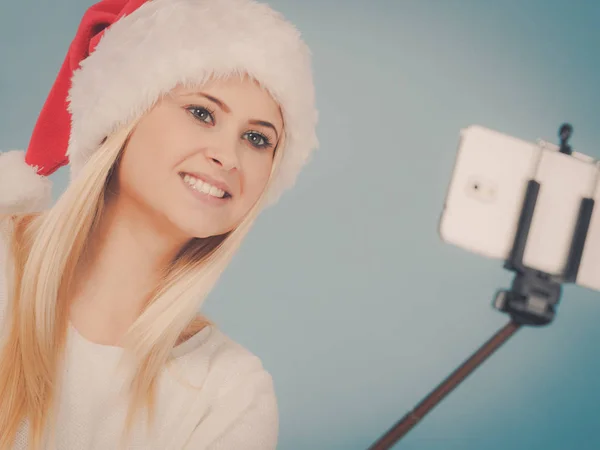 Dziewczyna w santa hat biorąc obraz siebie za pomocą selfie stick — Zdjęcie stockowe