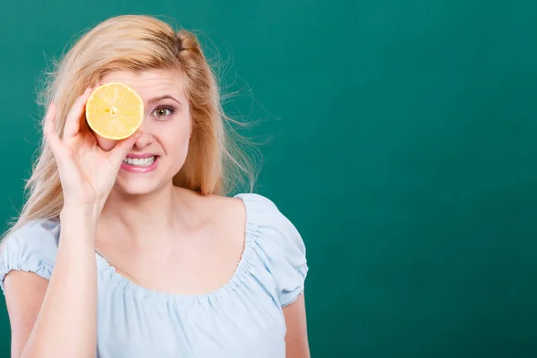 Meisje die haar oog met citroen citrusvruchten — Stockfoto