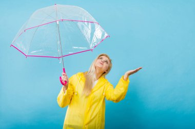 Hava kontrol şemsiye tutan yağmurluk giyen kadın