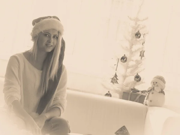 Kvinna i Santa hatt sitter på soffa avkopplande — Stockfoto