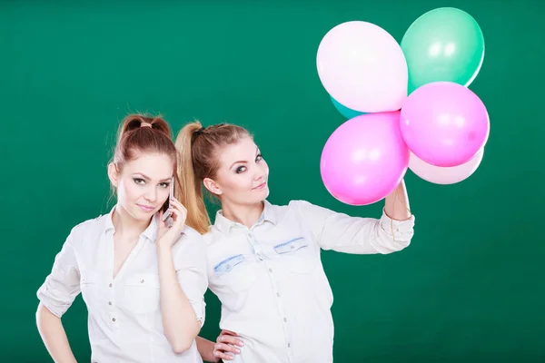 Dvě dívky s mobilním telefonem a balónky — Stock fotografie