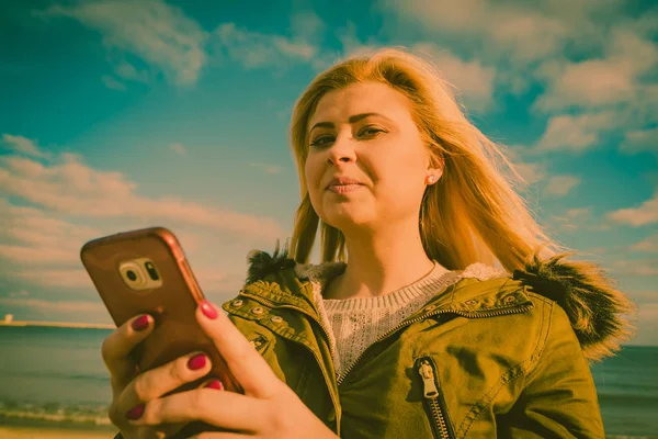 Mujer usando su teléfono inteligente fuera, día soleado — Foto de Stock