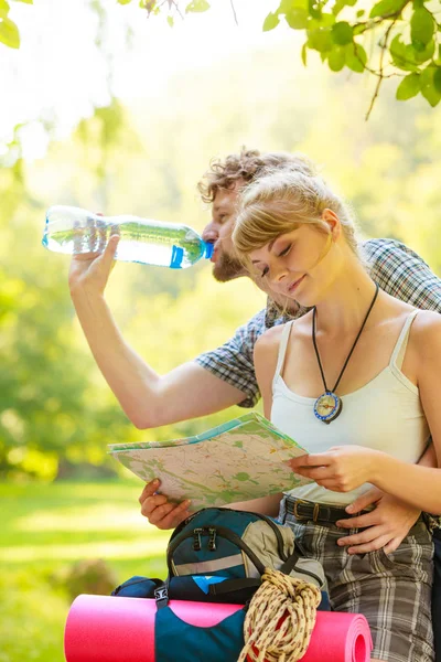 Casal caminhantes descansando na água potável da floresta — Fotografia de Stock