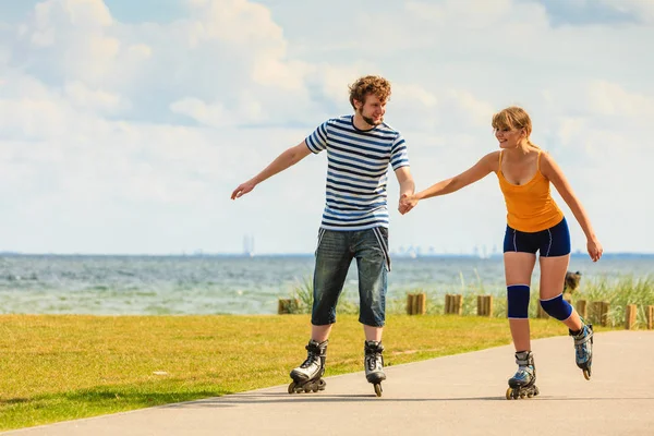 Pareja joven en patines de ruedas montando al aire libre — Foto de Stock