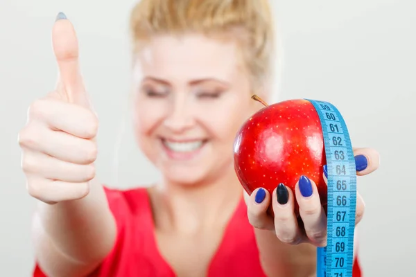 Happy woman holding apple and measuring tape — Stock Photo, Image