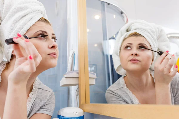 Mujer en el baño aplicando rímel en las pestañas — Foto de Stock