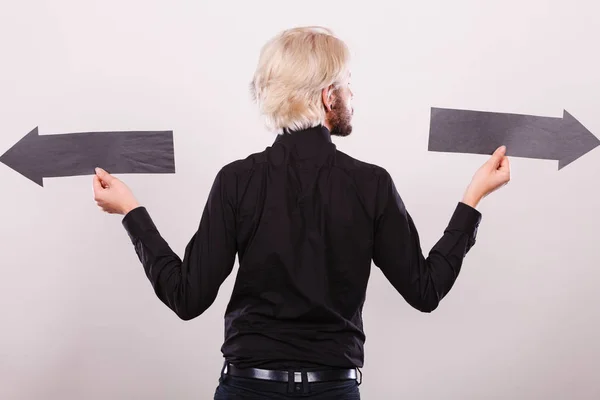 Hombre sosteniendo flechas negras apuntando a izquierda y derecha — Foto de Stock