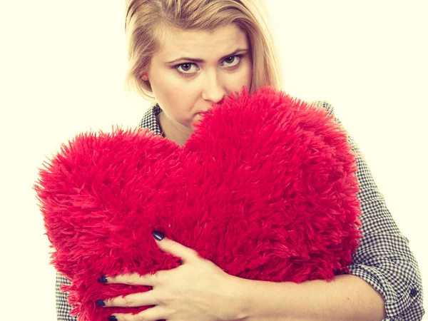 Chica triste sosteniendo gran almohada roja en forma de corazón — Foto de Stock