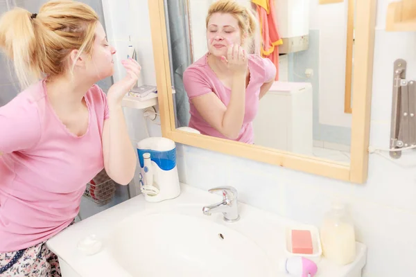 Mulher aplicando creme facial com o dedo — Fotografia de Stock