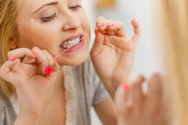 Mujer limpiando sus dientes usando hilo dental — Foto de Stock