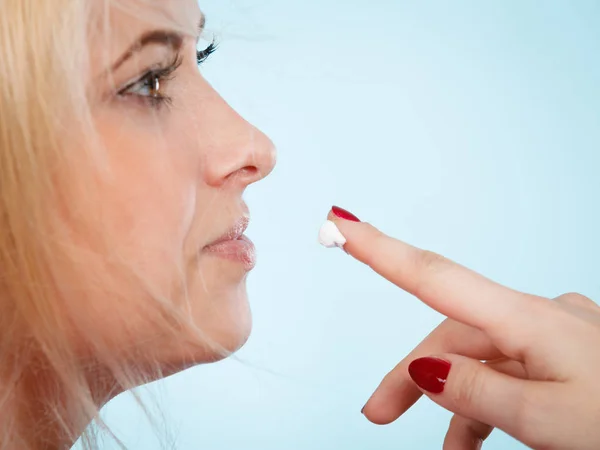 Woman applies lip balm cream to her lips