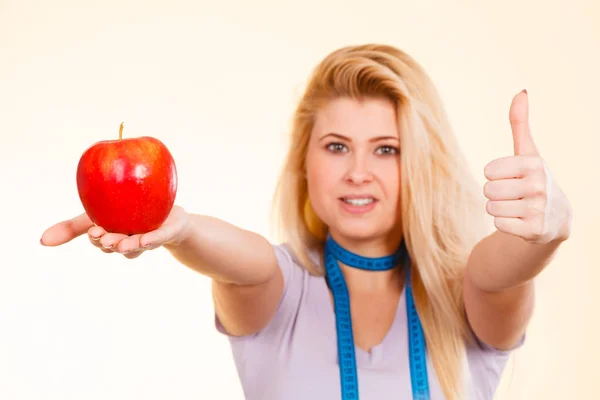 Woman with measuring tape around neck holding apple — Stock Photo, Image