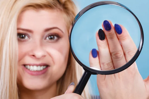 Femme regardant les ongles à travers la loupe — Photo