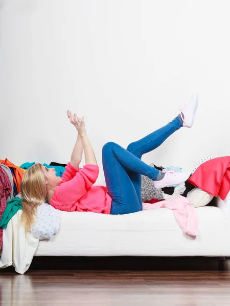 Woman does not know what to wear lying on couch