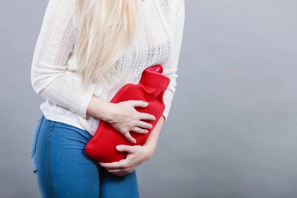 Femme sentiment crampes d'estomac tenant une bouteille d'eau chaude — Photo