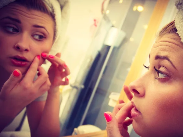 Vrouw op zoek bij de spiegel behandeling van acne — Stockfoto