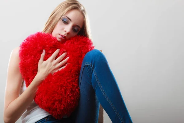 Smutný nešťastná žena drží červené srdce polštář — Stock fotografie