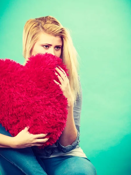 Mujer triste sosteniendo almohada roja en forma de corazón — Foto de Stock