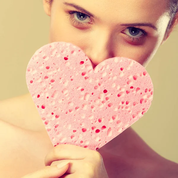 Donna che tiene in mano la spugna rosa del cuore . — Foto Stock