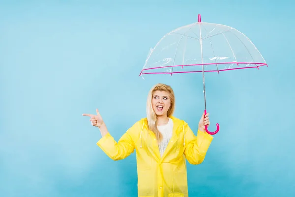 Mujer con impermeable sosteniendo paraguas apuntando — Foto de Stock
