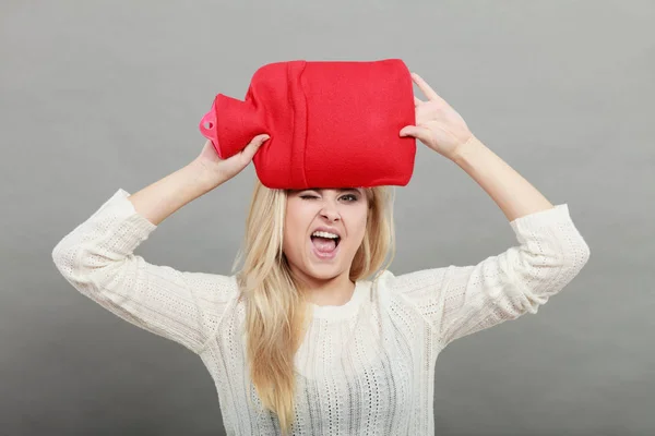 Woman holding red hot water bottle on head — Stock Photo, Image