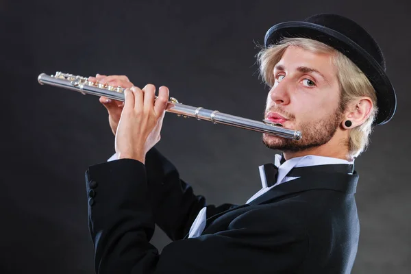 Элегантно одетый музыкант играет на флейте — стоковое фото