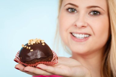 Çikolatalı kek tutan kadın ısırmak üzere.