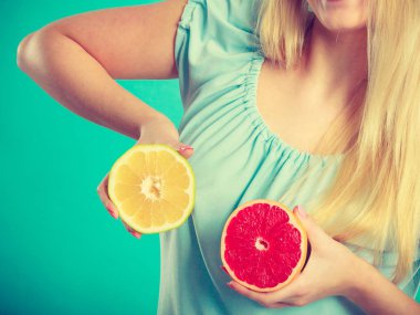 Kırmızı ve yeşil greyfurt tutan kadın