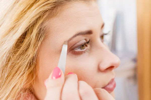 Woman tweezing eyebrows depilating with tweezers — Stock Photo, Image