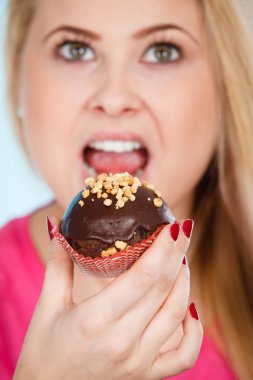 Çikolatalı kek tutan kadın ısırmak üzere.
