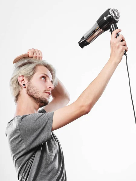 Young man drying hair with hairdryer — Stock Photo, Image