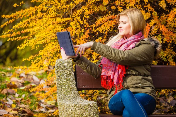 Nő ül a padon park tabletta segítségével pihentető — Stock Fotó