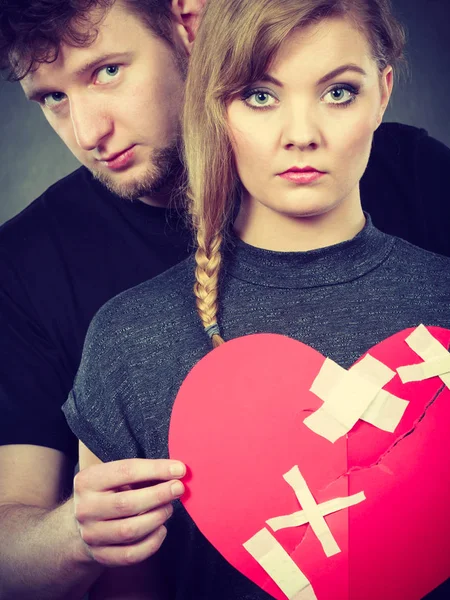 Sad couple holds broken heart.