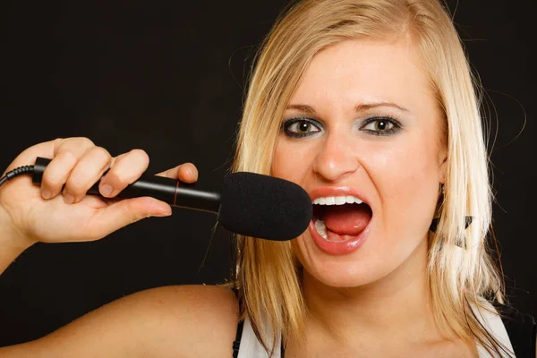 Blondi nainen laulaa mikrofoniin — kuvapankkivalokuva