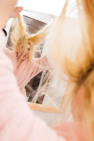 Donna guardando i suoi capelli biondi molto aggrovigliati — Foto Stock