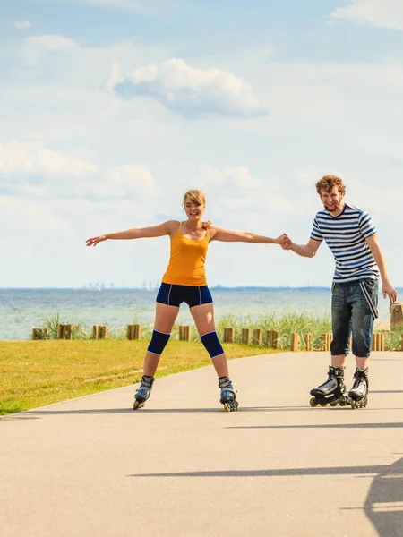 Jovem casal em patins andando ao ar livre — Fotografia de Stock