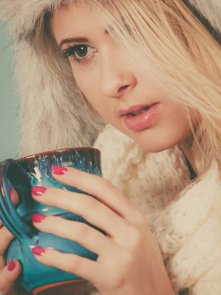 Женщина в зимней шляпе пьет из кружки — стоковое фото